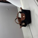 Black Longchamp Le Pliage Mini bag with brown accents on table.