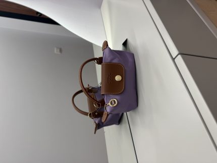 Çantë Longchamp Le Pliage Mini lila on white surface.