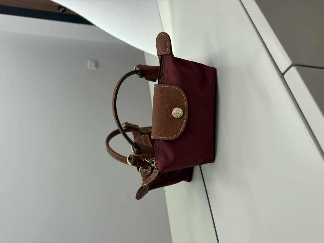 Bordo Longchamp Le Pliage Mini handbag on white surface.