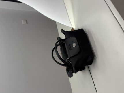 Black Longchamp Le Pliage Mini bag on white surface.