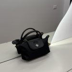Black Longchamp Le Pliage Mini bag on white surface.