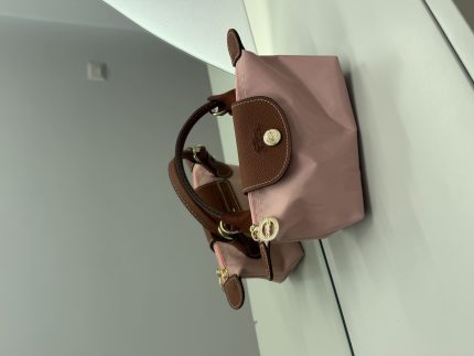 Pink Longchamp Le Pliage Mini handbag with brown leather accents.
