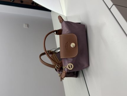 Çantë Longchamp Le Pliage Mini mauve on white surface.