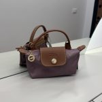 Çantë Longchamp Le Pliage Mini mauve në një sipërfaqe të bardhë.