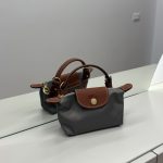 Çantë Longchamp Le Pliage Mini gri mbi një sipërfaqe të bardhë.