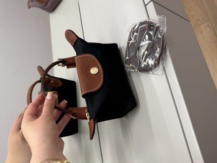 Black Longchamp Le Pliage Mini bag with brown handles and strap.
