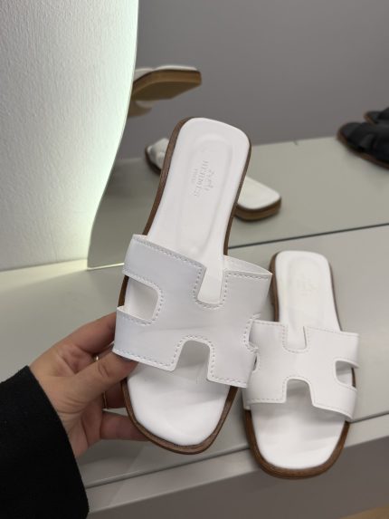 Hermes Oran Flat white sandals for women on display.