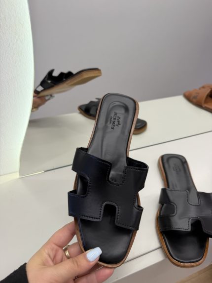Hermes Oran Flat black sandals for women on display.