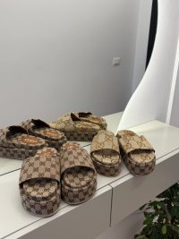 Gucci GG Monogram Platform sandals on display, mirrored reflection.