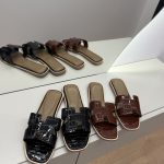 Hermes Flip-Flop Kelly in black and brown on display.