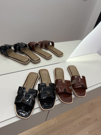 Hermes Flip-Flop Kelly in black and brown on display.