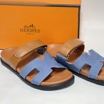 Hermes Chypre Denim/Kamel women's sandals with orange box background.