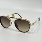 Gold-rimmed Dita sunglasses with gradient lenses on white background.