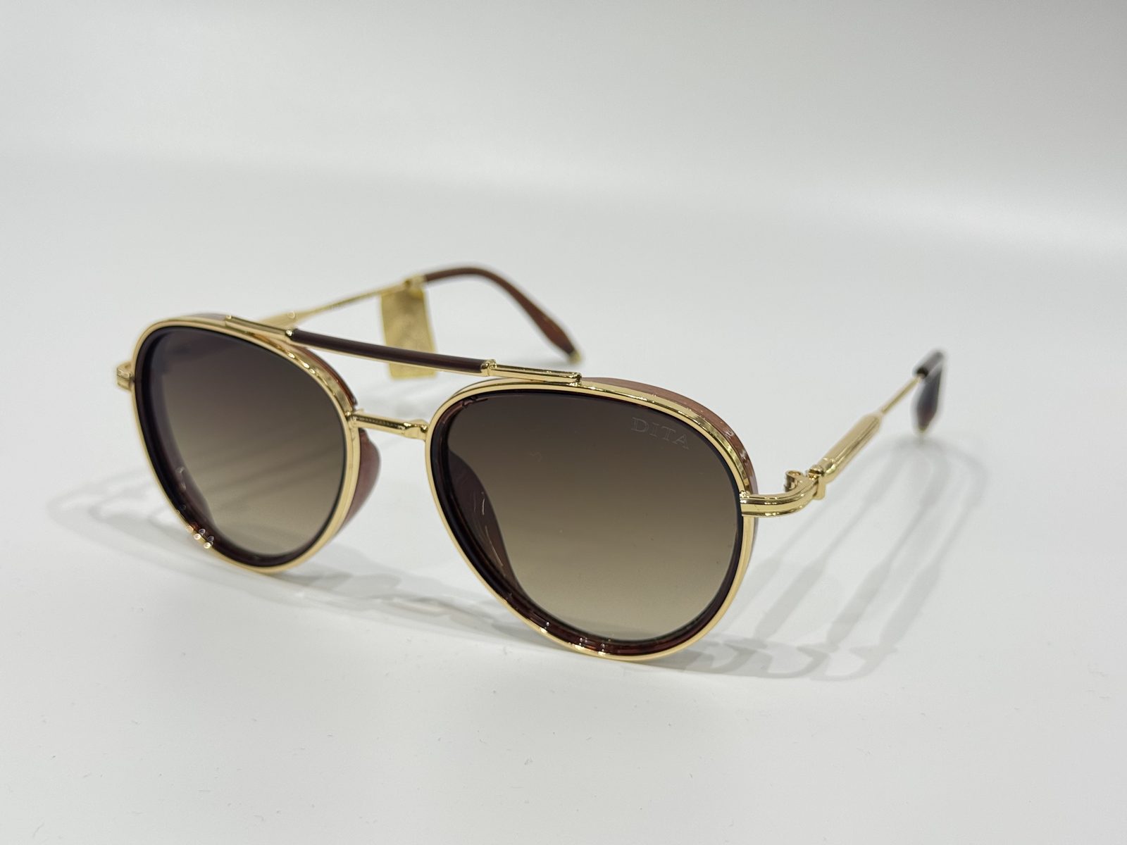 dita-3kryesore Gold-rimmed Dita sunglasses with gradient lenses on white background.