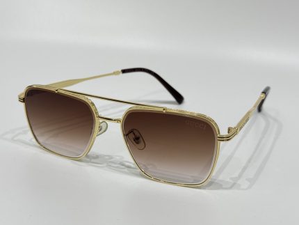 Gucci sunglasses with gold frame and gradient lenses on white background.
