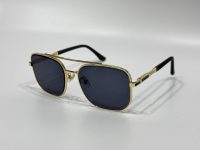 Gucci sunglasses with gold frame and dark lenses on white background.