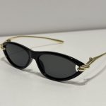 Bottega Veneta cat-eye sunglasses, black frame, gold accents, elegant design.