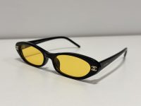 CHANEL oval sunglasses with yellow lenses, black frame.