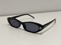 Chanel oval sunglasses, black frame, gold logo, stylish design.