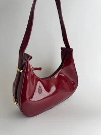Elegant burgundy women's handbag with sleek design and gold accents.