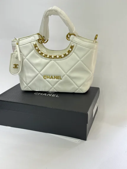 Çantë moderne për femra CHANEL, dizajn elegant e bardhë me detaje ari.