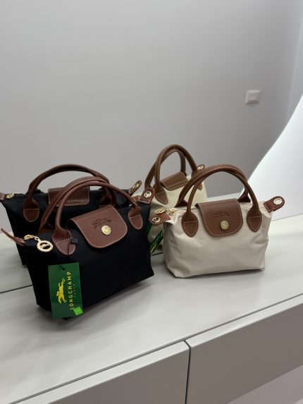 Çantë Femrash Longchamp handbags in black and beige on display.