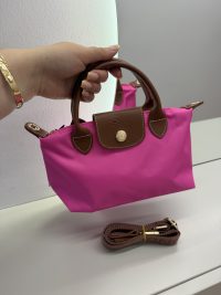 Pink Longchamp handbag with brown leather handles and strap.