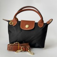 Çantë Femrash Longchamp black handbag with brown leather accents.