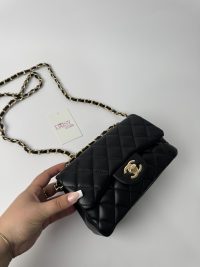Black Chanel classic quilted handbag with gold chain strap.