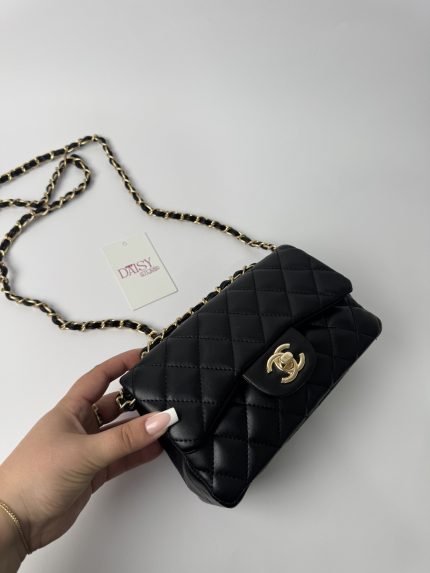 Black Chanel classic quilted handbag with gold chain strap.