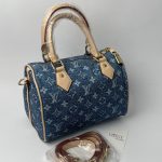 Blue denim handbag with beige handles and detachable strap.