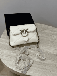 White quilted mini puff bag with chain strap on table.