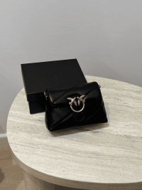 Black Pink Love Mini Puff handbag on table.
