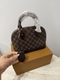 Louis Vuitton Alma Medium handbag on box, checkered pattern.