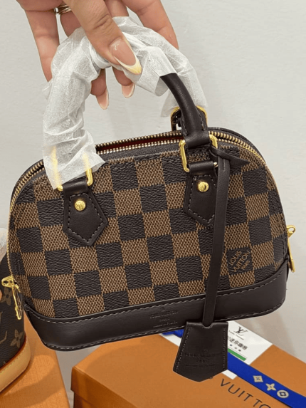Louis Vuitton Alma Mini handbag with checkered design and gold accents.