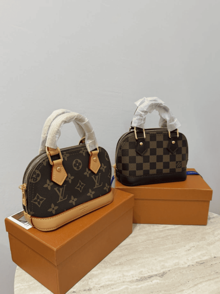 Louis Vuitton Alma Mini handbags on display boxes.