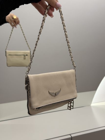 Elegant beige handbag with chain strap and wing emblem.