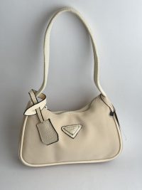 Prada Re-Edition Mini çanta femrash, krem ngjyrë, dizajn elegant.
