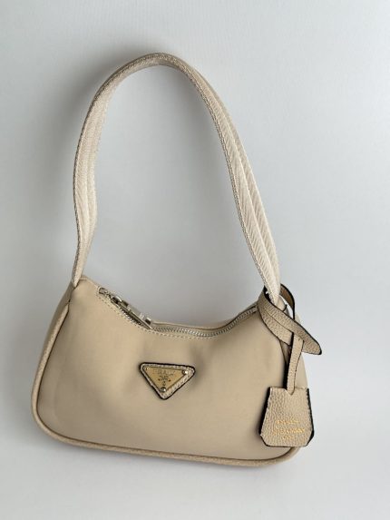 Prada Re-Edition Mini beige handbag with logo and strap.
