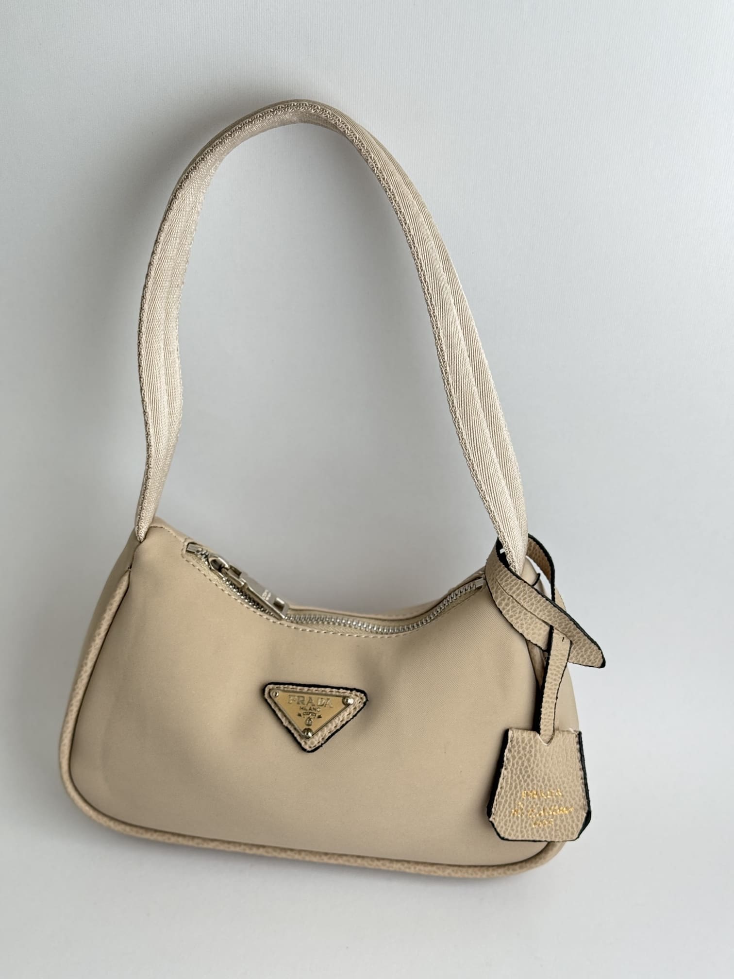 ds-canta-104-kryesore Prada Re-Edition Mini beige handbag with logo and strap.