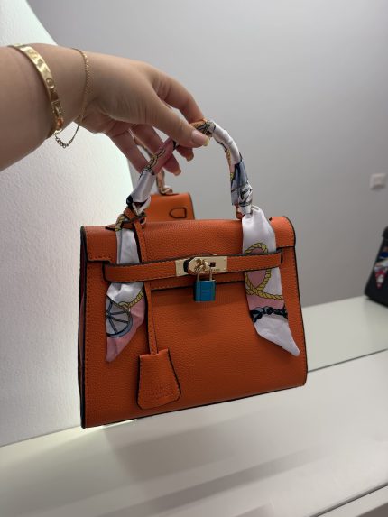 Orange Hermes Kelly Mini handbag with scarf-wrapped handle.