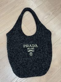 Prada Boucle beach bag with logo on wooden floor.