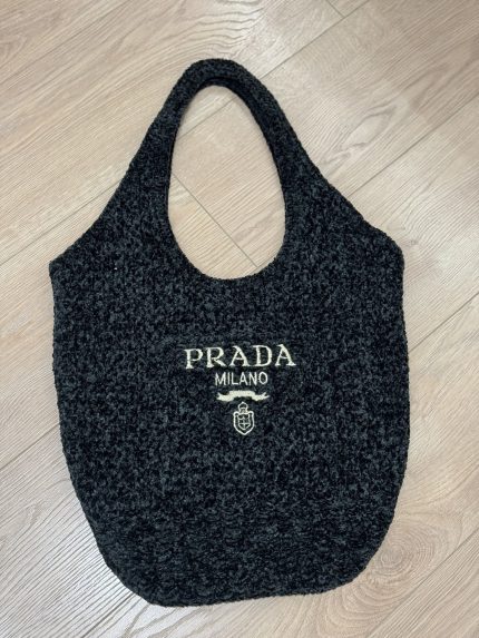 Prada Boucle beach bag with logo on wooden floor.