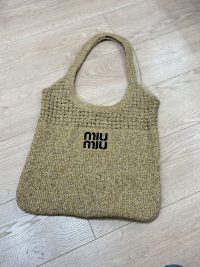 Miu Miu beach bag, elegant woven design on wooden floor.