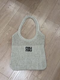 Miu Miu beach bag, elegant woven design on wooden floor.