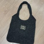 Black Miu Miu beach bag on wooden floor.