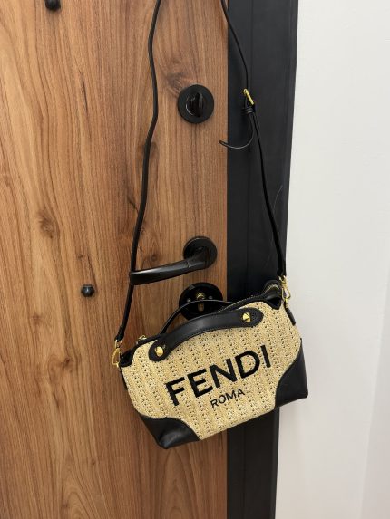 Fendi Roma beach bag with black accents hanging on wooden door.