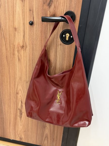Çanta femrash YSL Hobo, elegancë dhe stil, ngjyrë e kuqe, në derë.