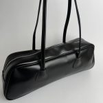 Black boxy women's handbag with zipper and long handles.