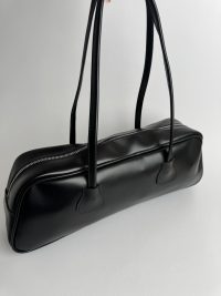 Black boxy women's handbag with zipper and long handles.